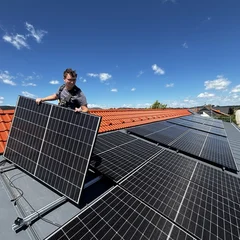 Anzeigenbild der Lumitra-Kampagne: Monteur richtet ein Solarmodul auf einem Ziegeldach aus
