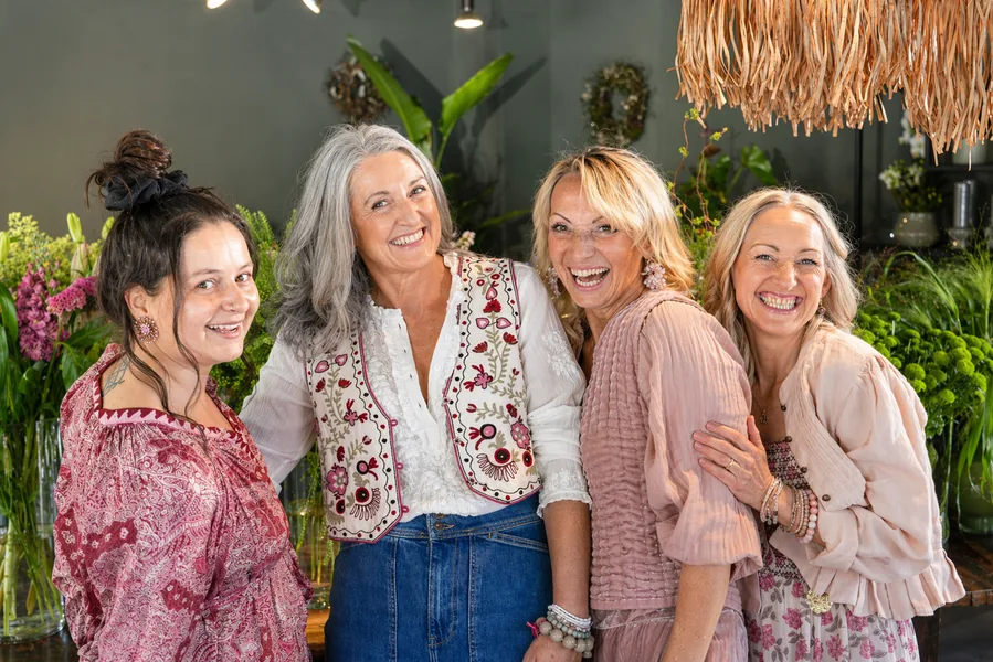 Vier Frauen in Pura-Outfits lachen zwischen Blumen im Laden