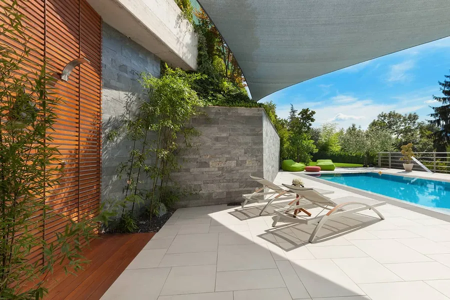 Pool-Anlage mit heller Terrasse, Liegen und Holzfassade