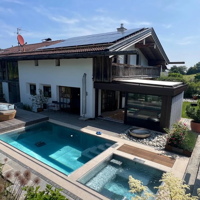 Pool-Anlage von Gartengestaltung Rosenheim in Vagen: Pool mit Whirlpool, Holzdeck und Kiesbeet vor einem Wohnhaus