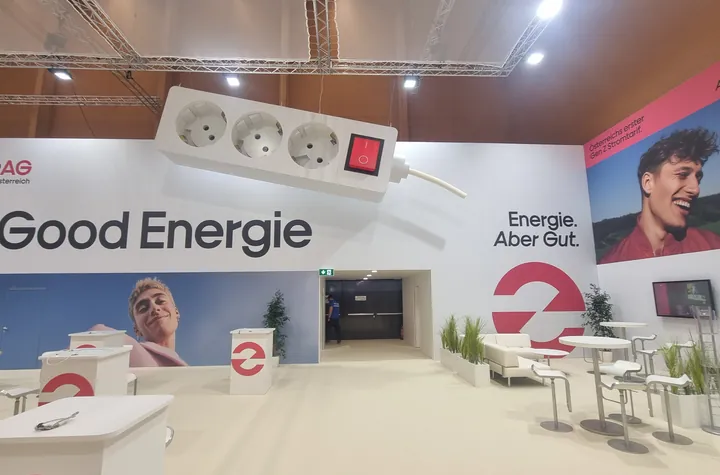 Offener Messestand mit großen Bildwänden und Tischen